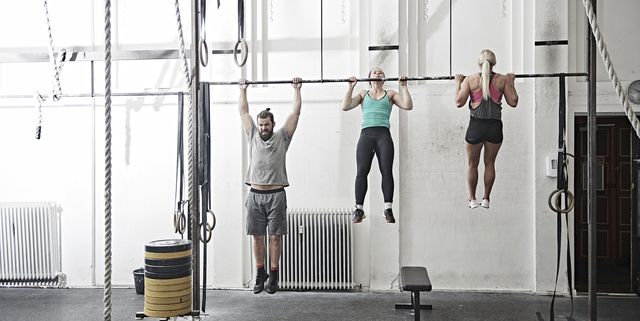Friends doing chin-up in cross training gym