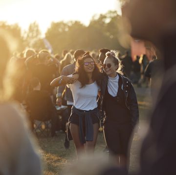 twee meiden lachend op een festivalterrein bij zonsondergang