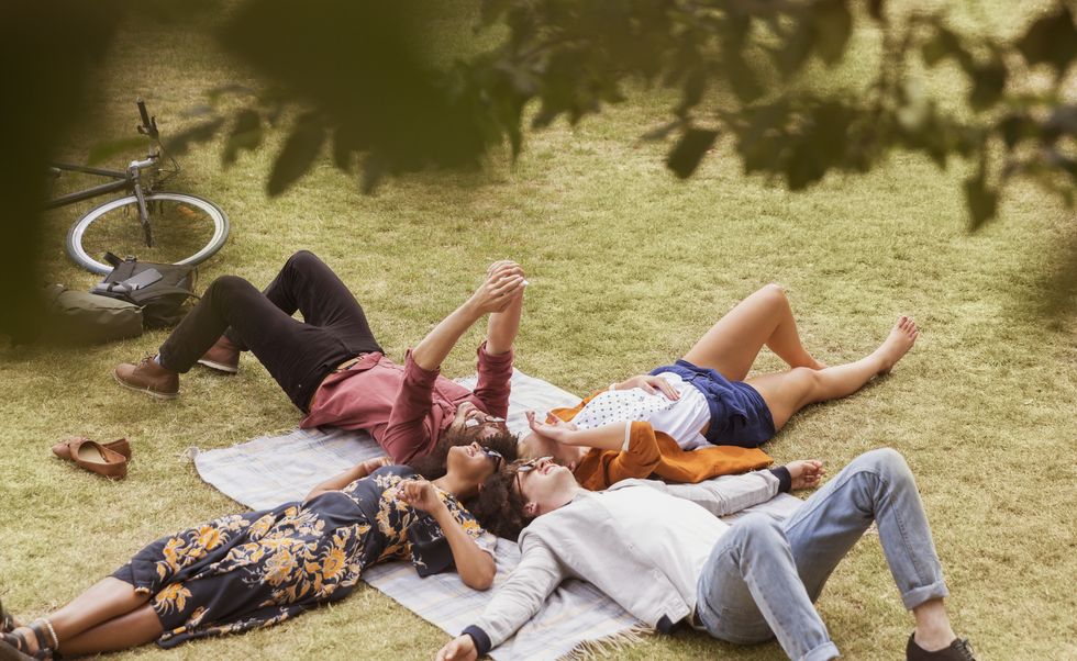 Friends taking selfie laying in circle on blanket in park