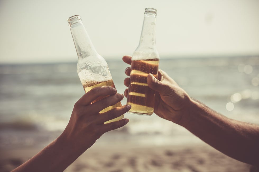 friends toasting with beer bottles at the beach