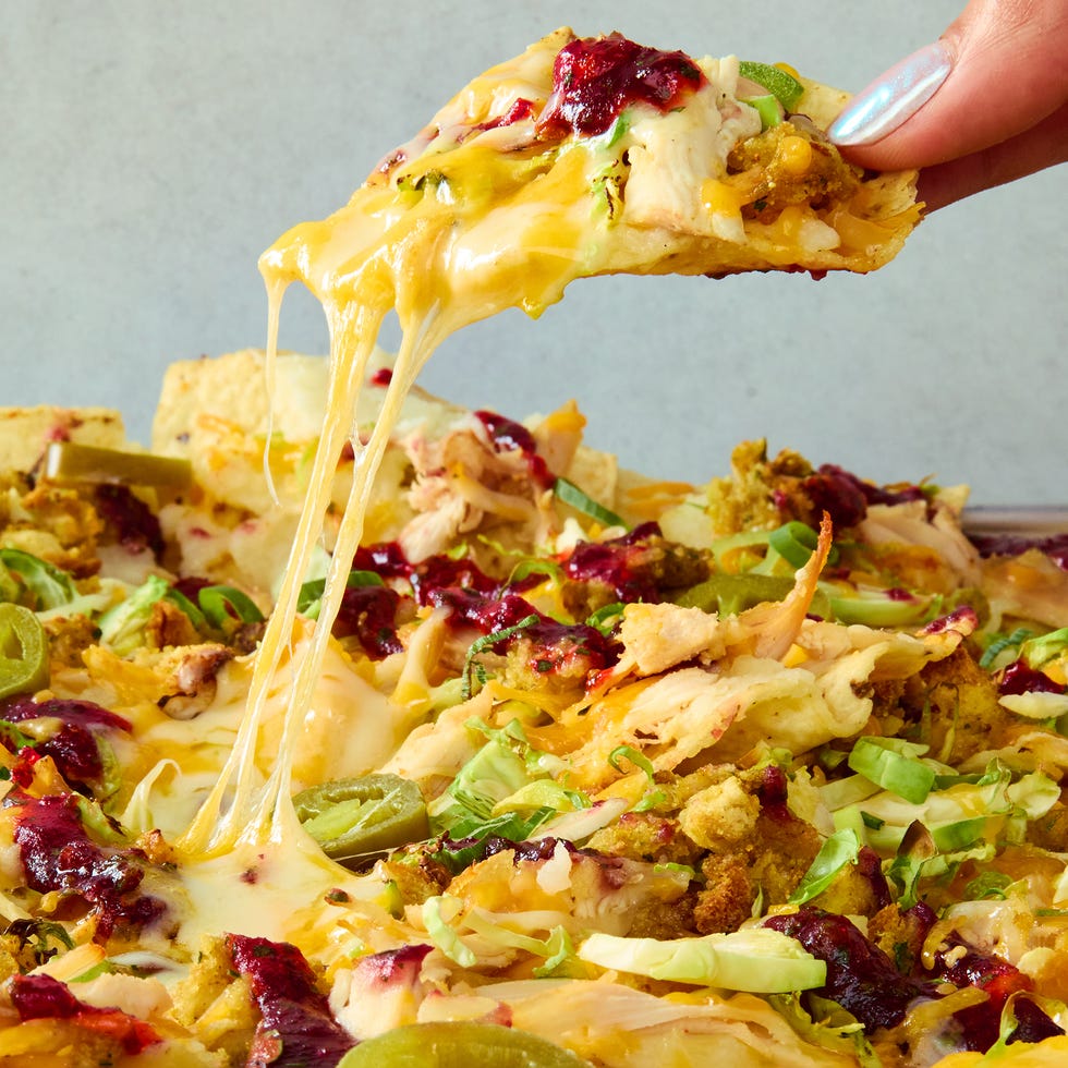 tortilla chips on a sheet tray topped with melted cheese, turkey, stuffing, cranberry sauce, and jalapenos