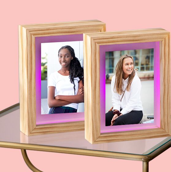 two light up picture frames on glass table with pink background
