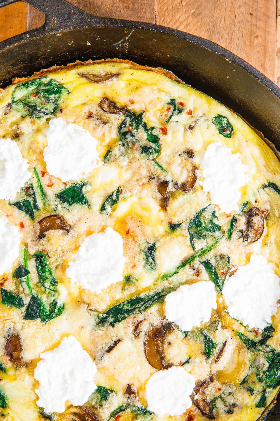 closeup of a frittata with mushrooms, spinach, and cheese