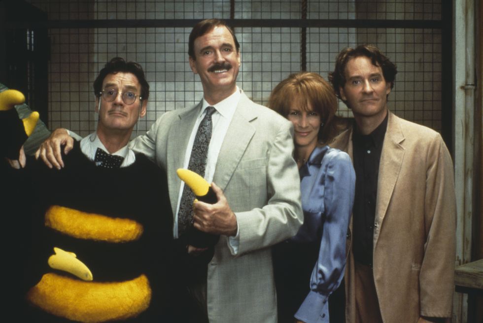actors michael palin, john cleese, jamie lee curtis and kevin kline standing next to each other and smiling, looking into the camera, on the set of a film