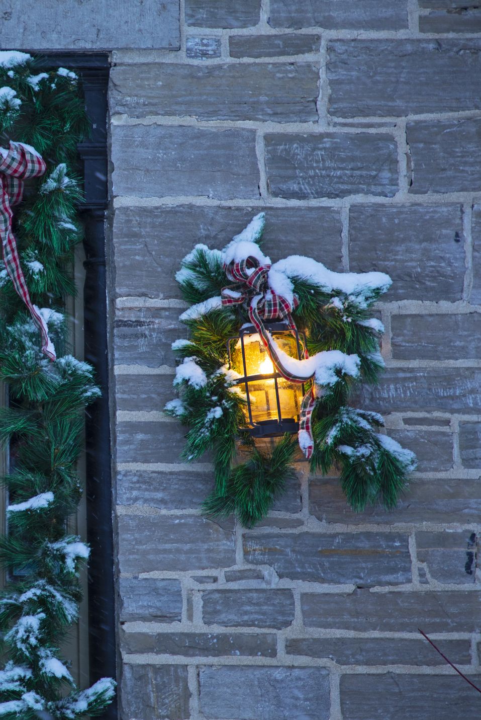 front door and porch light on old stone house at christmas