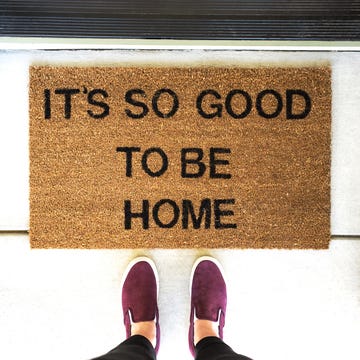 person standing in front of a welcome mat that says it's so good to be home