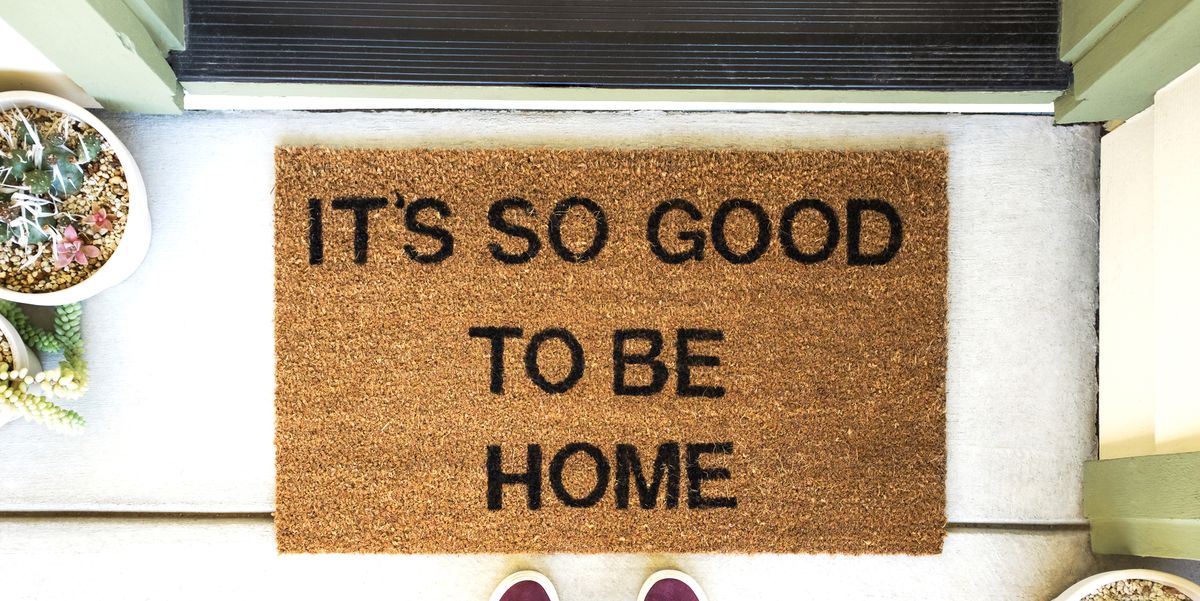 person standing in front of a welcome mat that says it's so good to be home