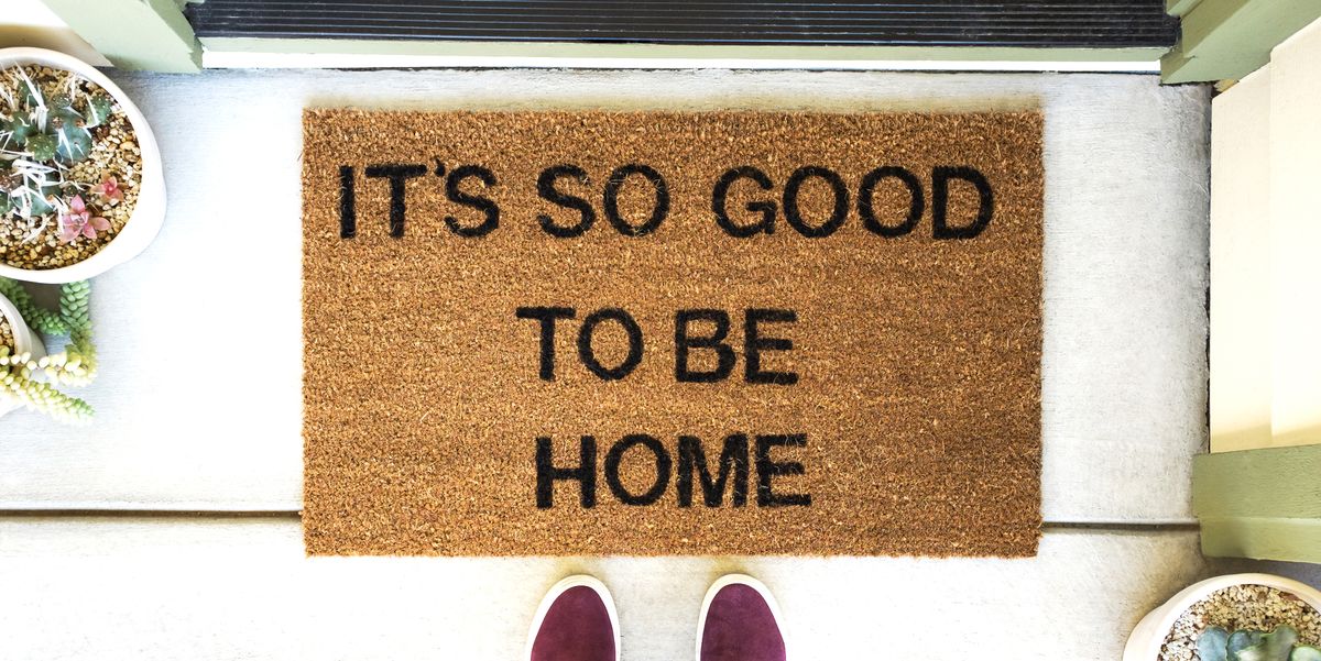 person standing in front of a welcome mat that says it's so good to be home