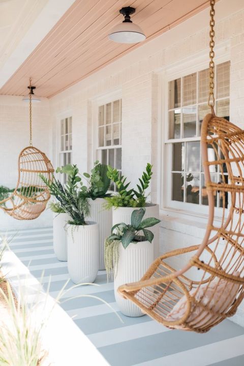 front porch with floor painted in stripes of gray and white with hanging chairs and tall white planters filled with plants