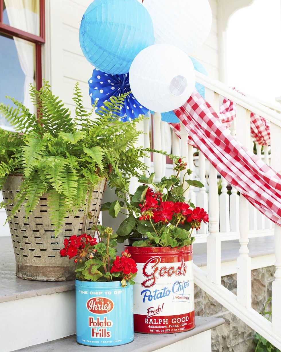 vintage potato cans filled with flowers and greenery sit on porch stairs