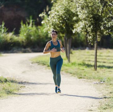 front view of a hispanic woman with ponytail running on park road