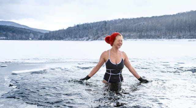 front view of active senior woman in swimsuit outdoors in water in winter, cold therapy concept