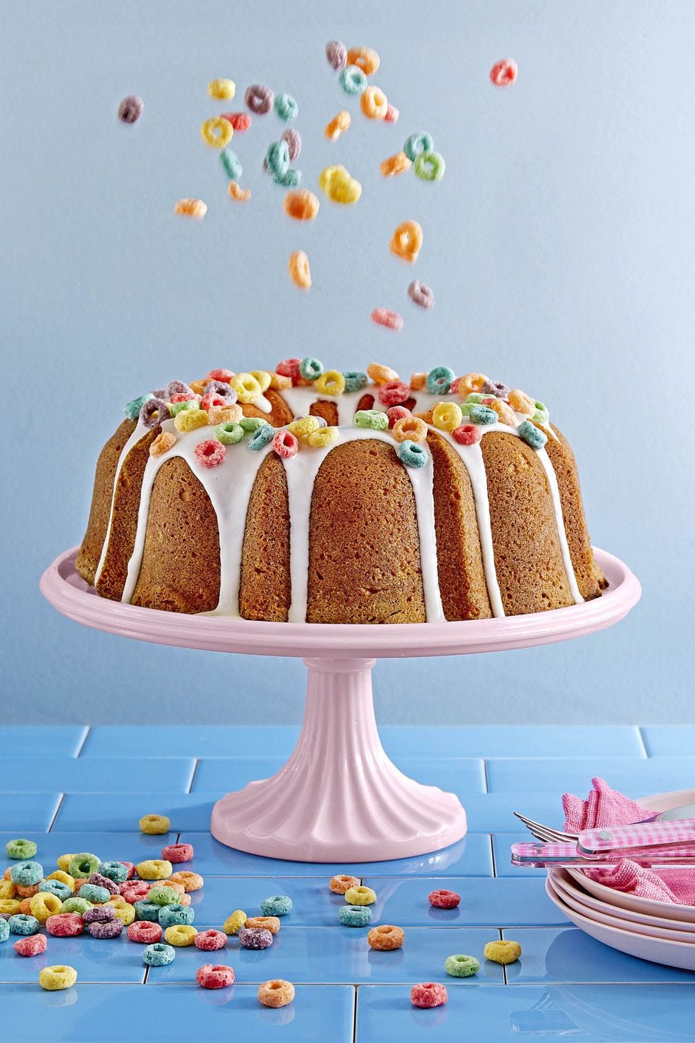 froot loops cake  with icing drizzle froot loops on top, served on a pink cake stand