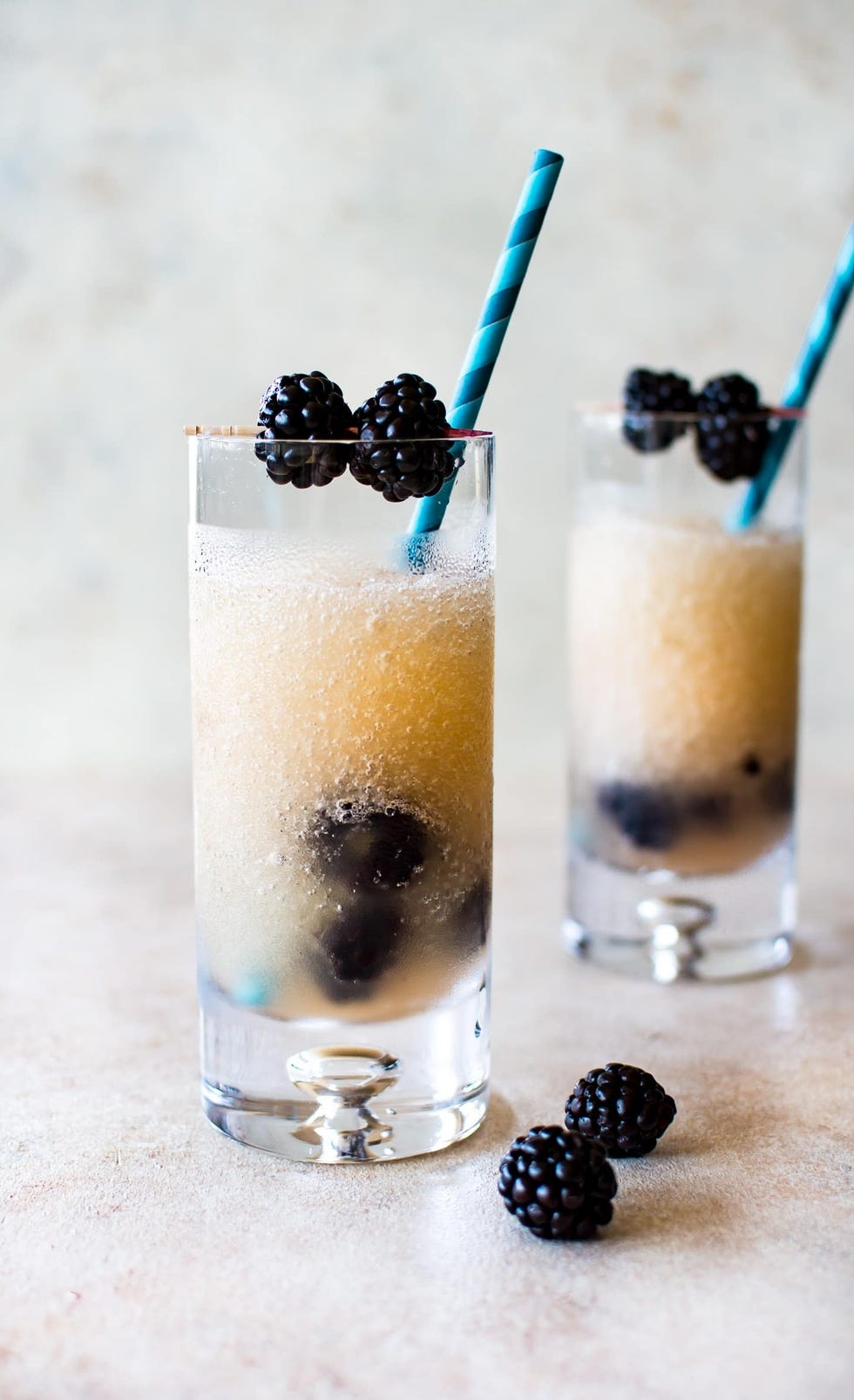 frozen blackberry friesling in small glasses and garnished with blackberries and paper straws