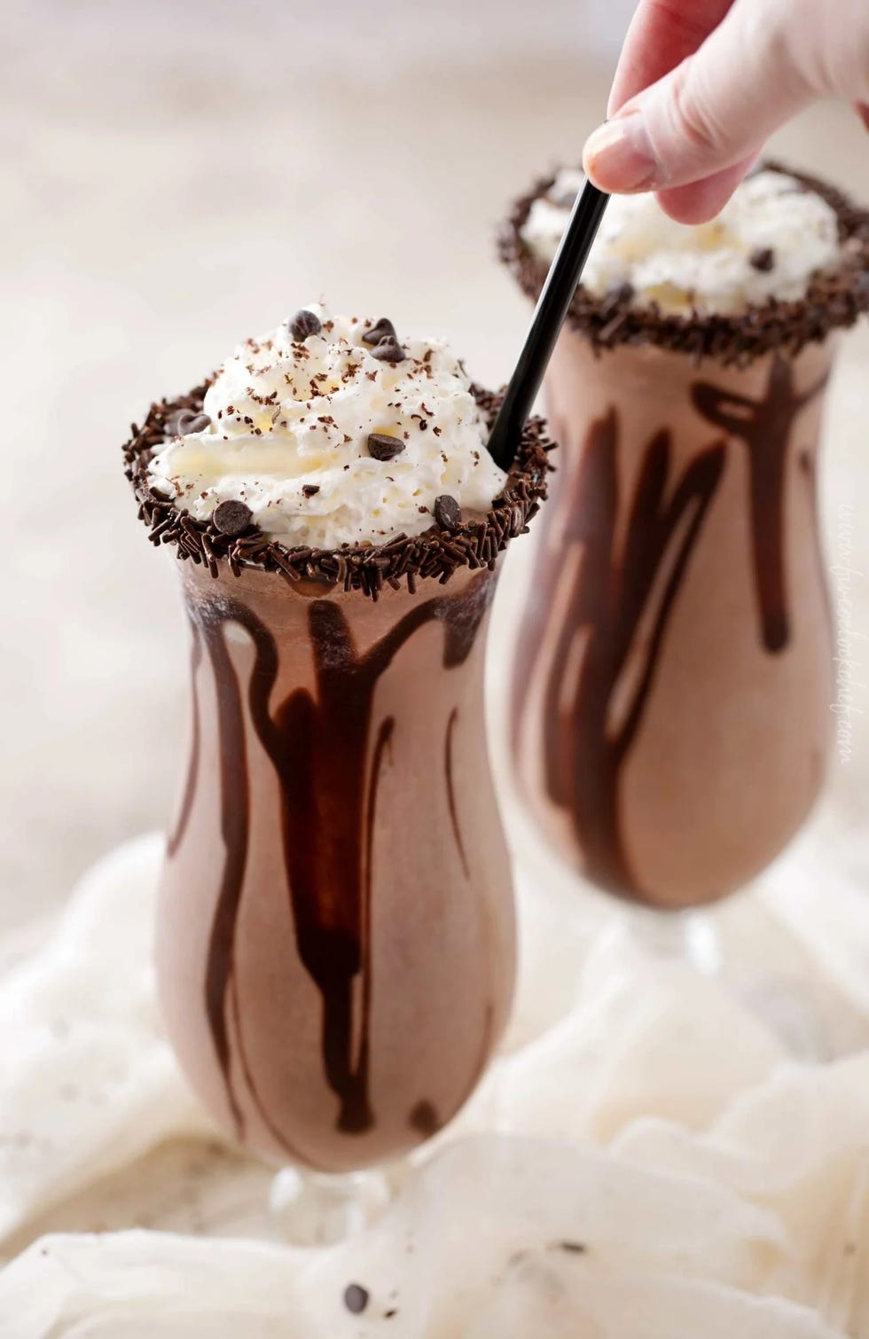 frozen chocolate mudslide in a tall glass with whipped cream on top and chocolate sprinkles around the rim