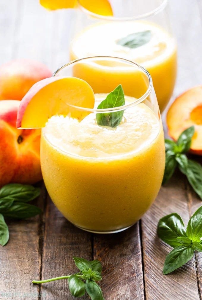 peach basil frose in a glass with a fresh peach slice for garnish