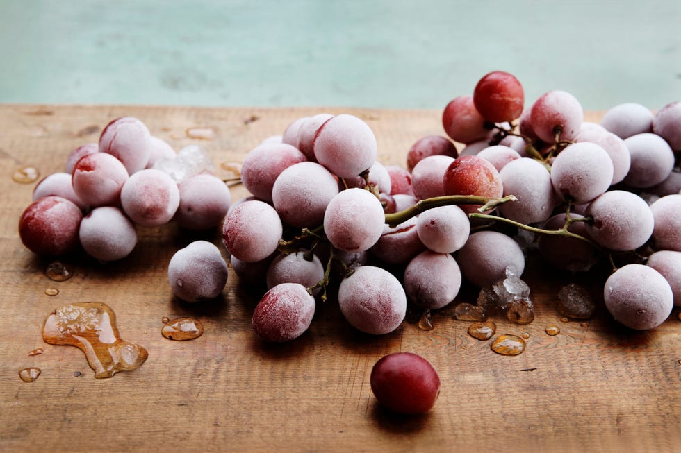 Frozen red grapes on wooden chopping board