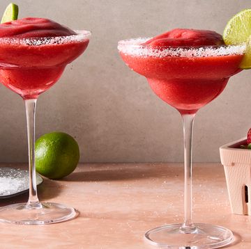 frozen strawberry margarita in glass with a salt rim and lime garnish