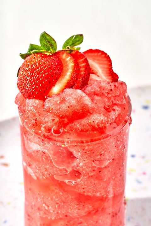 a frozen red drink in a glass garnished with strawberries