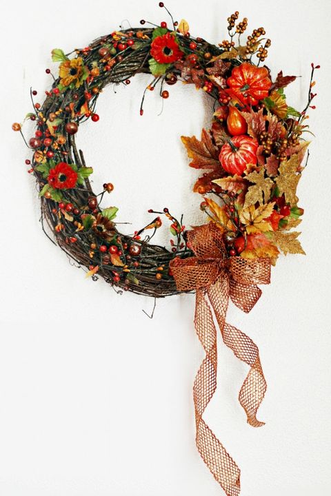 wreath decorated with faux pumpkins, berries and leaves and a ribbon on it