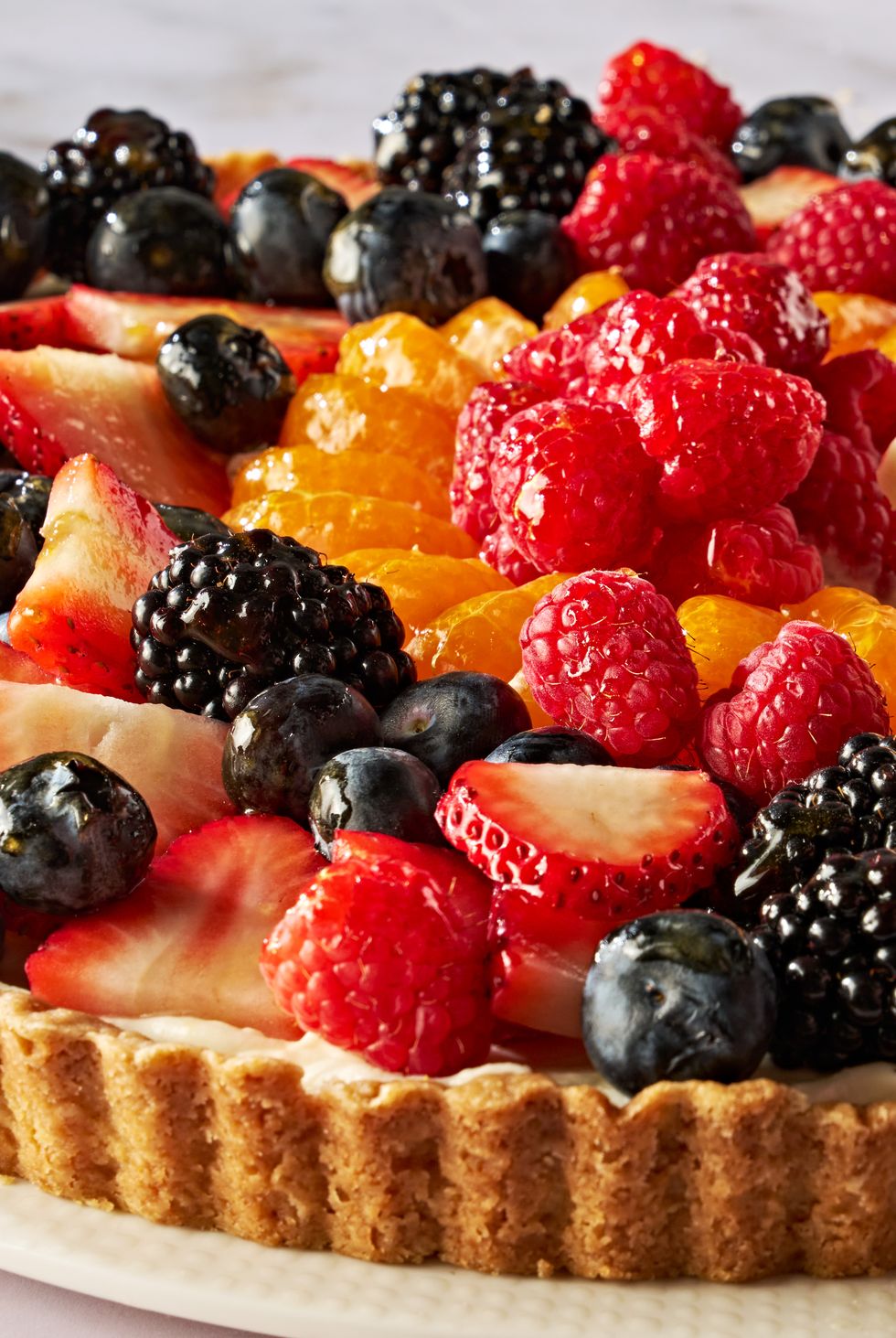tart topped with blueberries, raspberries, sliced strawberries, blackberries, and orange slices