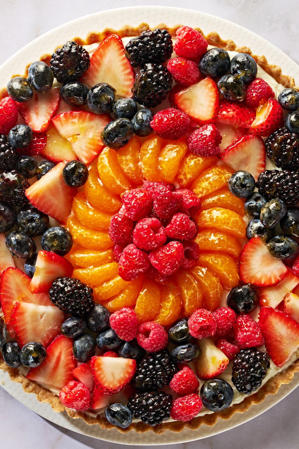 tart topped with blueberries, raspberries, sliced strawberries, blackberries, and orange slices