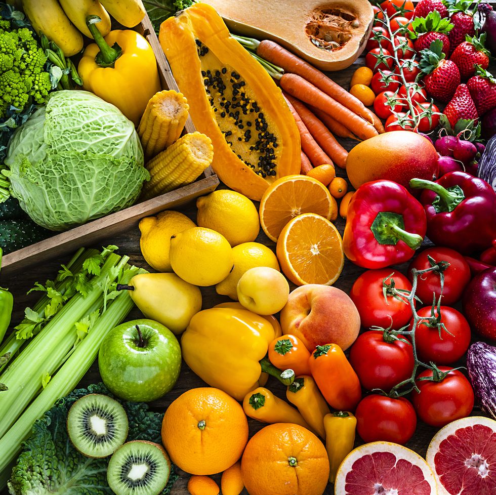 high angle view of a large assortment of healthy fresh rainbow colored organic fruits and vegetables the composition includes cabbage, carrots, onion, tomatoes, raw potato, avocado, asparagus, eggplant, celery, cucumber, broccoli, squash, lettuce, spinach, lemon, apples, pear, strawberries, papaya, mango, banana, grape fruit, oranges, kiwi fruit among others the composition is at the left of an horizontal frame leaving useful copy space for text andor logo at the right high resolution 42mp studio digital capture taken with sony a7rii and zeiss batis 40mm f20 cf lens