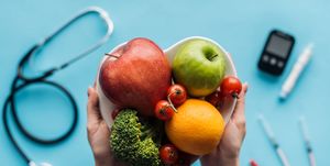 fruits and vegetables in female hands with medical equipment on blue background