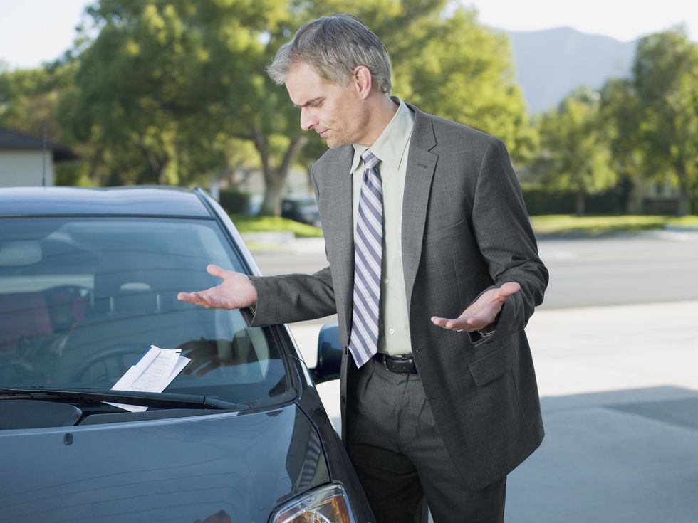 frustrated businessman viewing parking ticket on windshield
