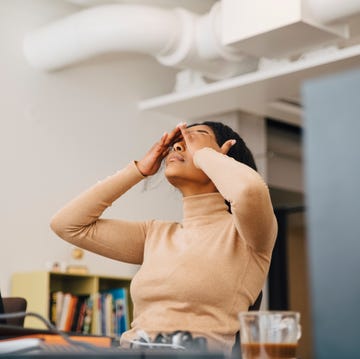 frustrated female computer programmer with head in hands sitting in creative office