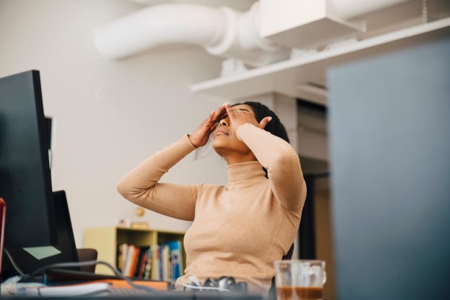 frustrated female computer programmer with head in hands sitting in creative office