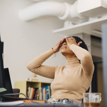 frustrated female computer programmer with head in hands sitting in creative office