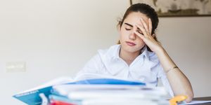frustrated female student with documents at desk at home