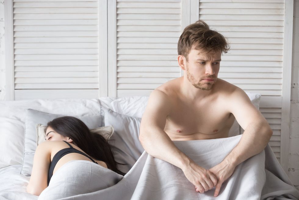 frustrated man and sleeping woman lying in bed
