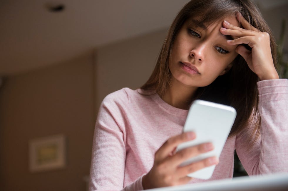 frustrated mixed race woman texting on cell phone