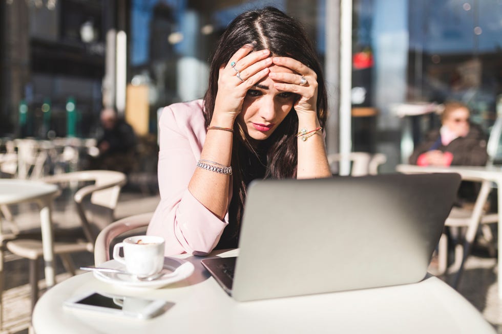 Frustrated young businesswoman using laptop at an outdoor cafe