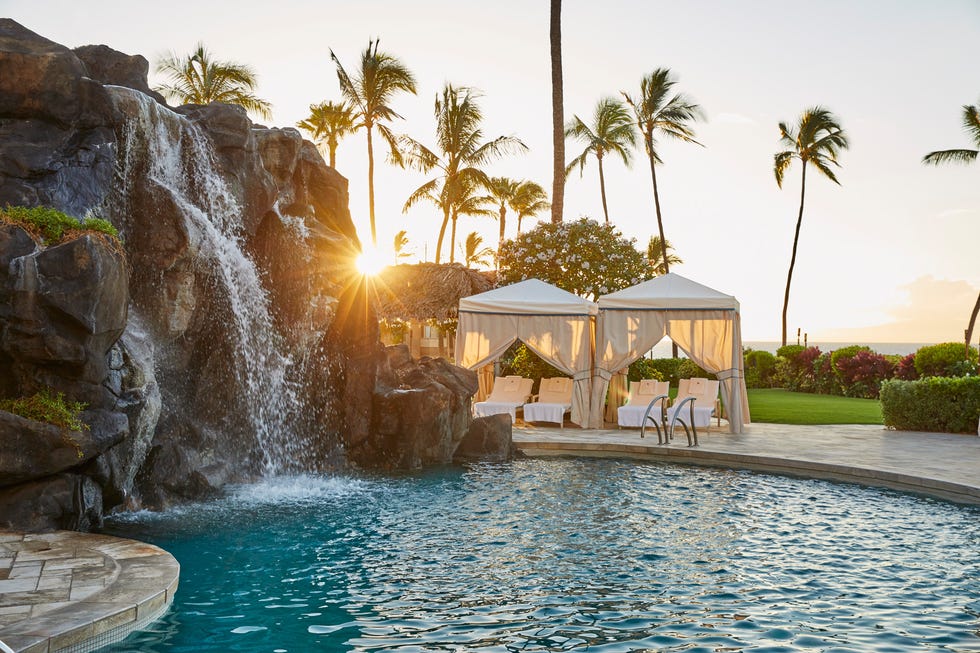 a pool with a waterfall and umbrellas by a waterfall