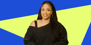 a person wearing a black offshoulder sweatshirt with long hair against a vibrant blue and yellow background