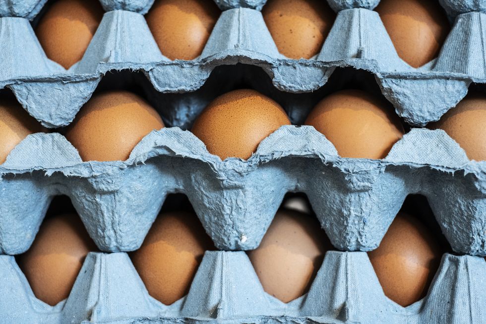 full frame close up of a stack of blue cartons with brown eggs