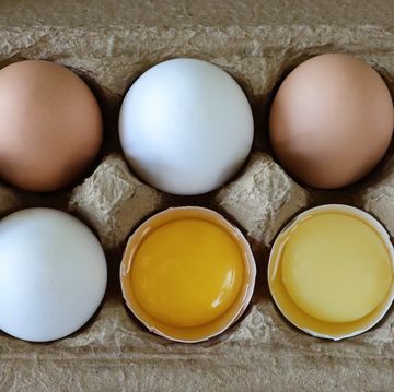 full frame image of ten mixed coloured chicken eggs, five white and five brown alternating shells, two broken eggs with view of yolk and albumen, elevated view