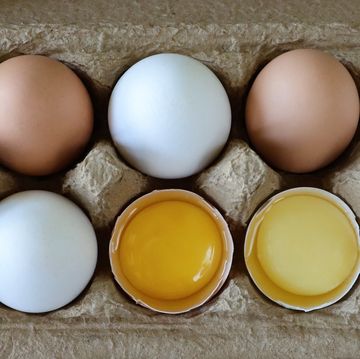full frame image of ten mixed coloured chicken eggs, five white and five brown alternating shells, two broken eggs with view of yolk and albumen, elevated view