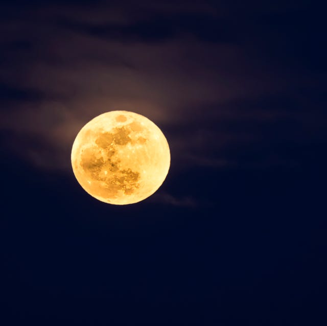 Full frame of the Supermoon of yellow color on a black sky with some high clouds. Valencia, Spain
