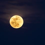 Full frame of the Supermoon of yellow color on a black sky with some high clouds. Valencia, Spain