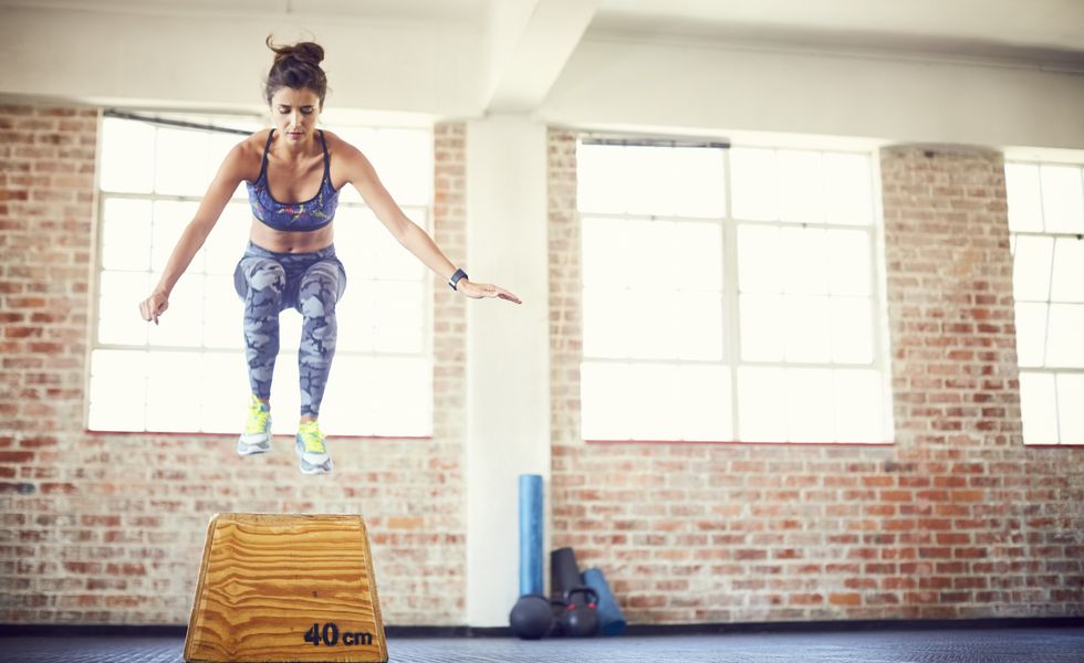 Full length of fit female athlete jumping over box
