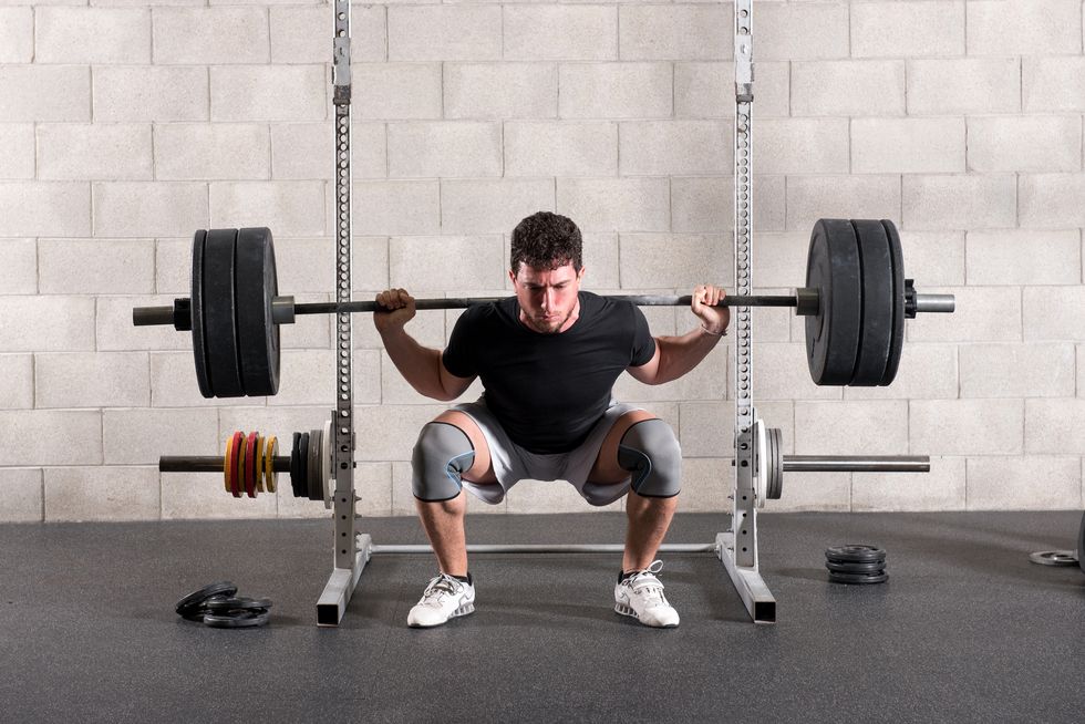 full length of man lifting barbell ln gym