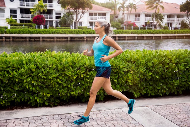 Full length of sporty mature woman running on footpath