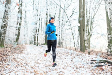 full length of woman jogging in forest during winter