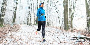 full length of woman jogging in forest during winter