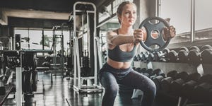 Full Length Of Woman Lifting Weight In Gym