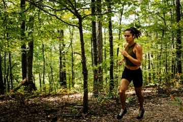 full length of woman running in forest